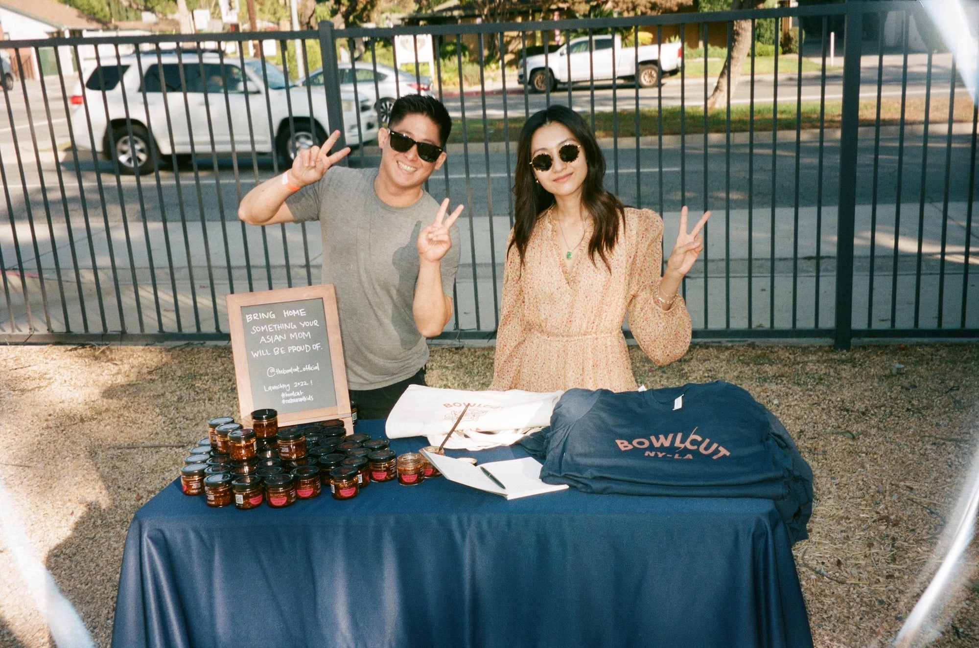 A pop-up table with a navy tablecloth, a sign and bottles of sauce