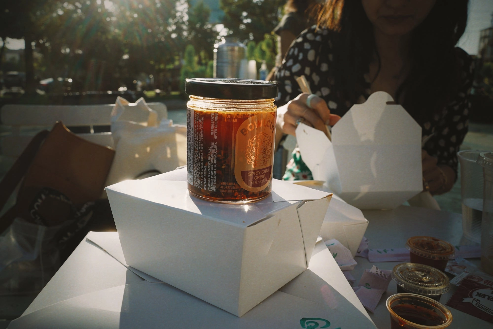 A jar of chili sauce sitting in a white takeout box